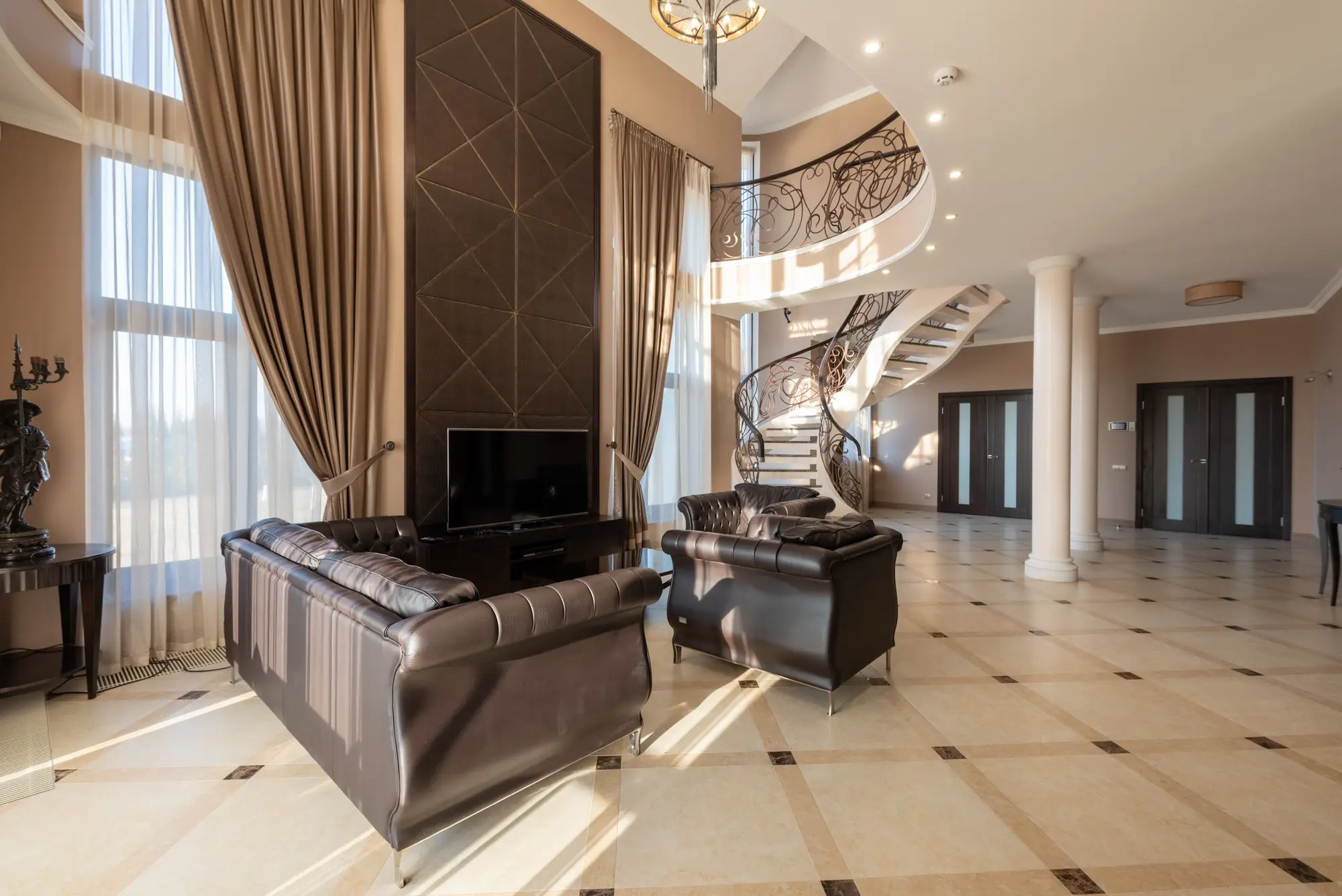 A grand living space with a curved staircase within a Hilwa Heights residence