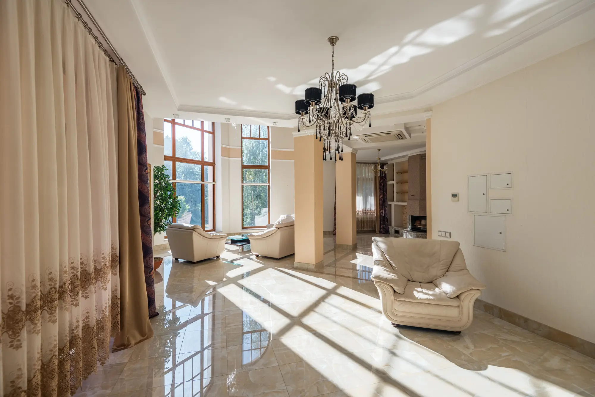 A sunlit living room with tall windows and comfortable seating, prepared for arrival